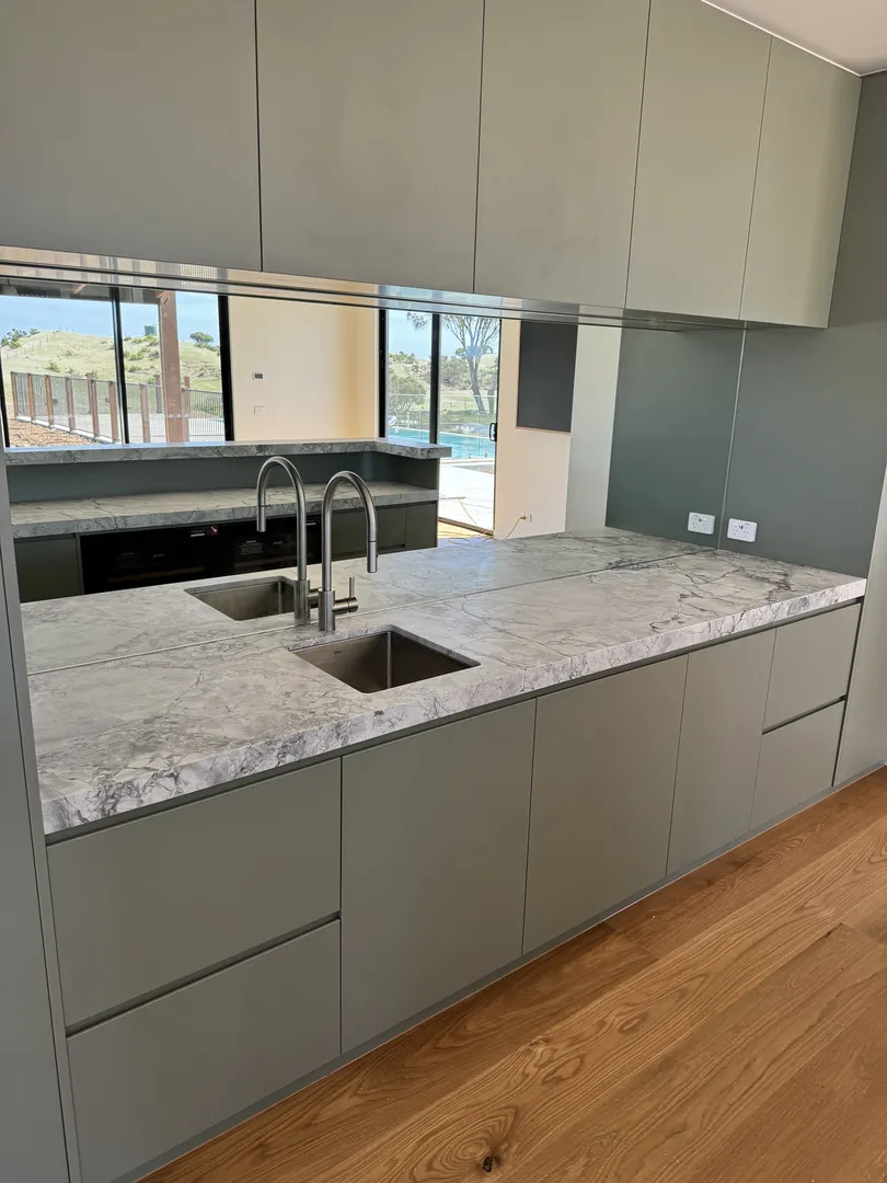 Modern kitchen with marble countertops and double sinks.
