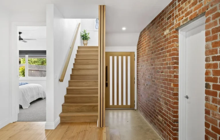 Hallway with stairs, wooden door, brick wall
