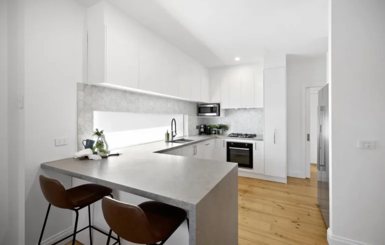 Modern white kitchen with marble backsplash and island.